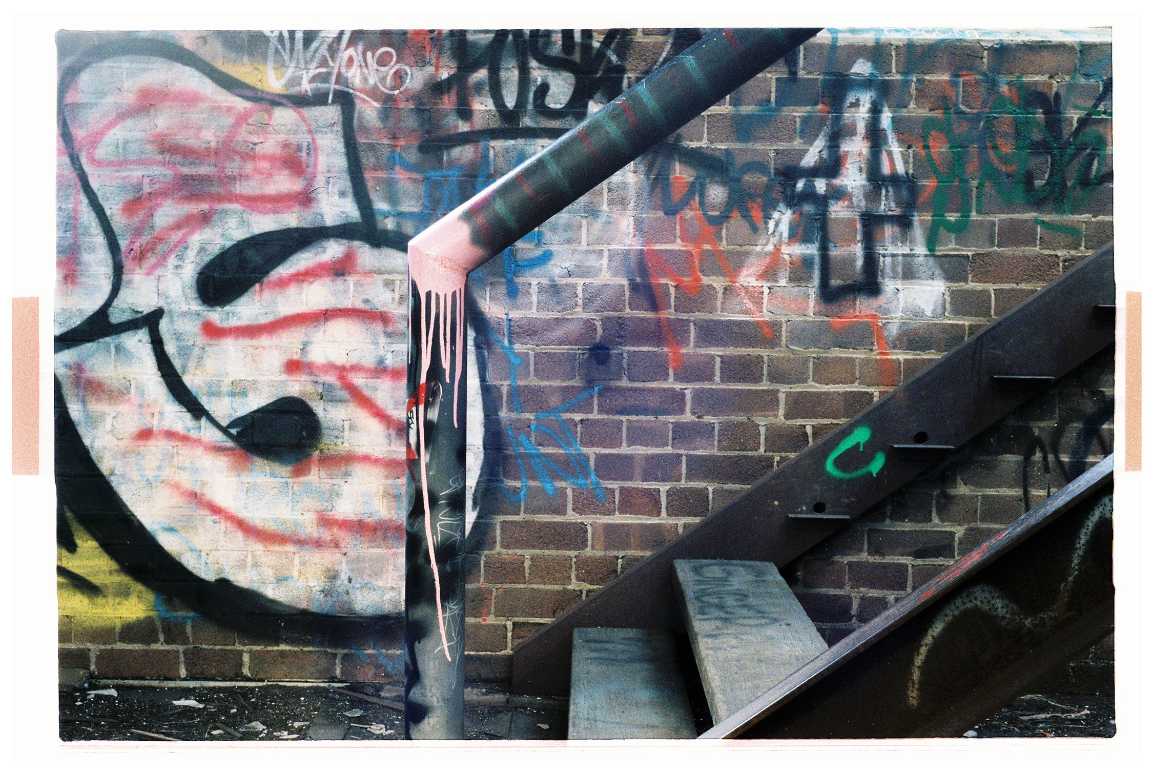 Colourful graffiti is sprayed all over bricks, hand rails of a a broken staircase